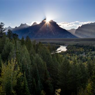 The sun sets behind Grand Teton bathing the landscape below in warm yellow light for it's final moments before night comes.  