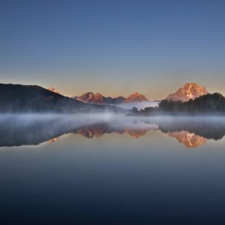 The mist begins to burn off of Oxbow Bend as the sun rises to warm a very chilly morning. The moon is trying to hold on before the sun claims the day.